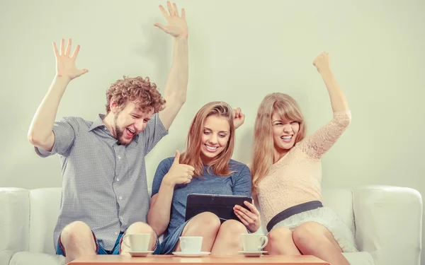 Exitosos amigos felices con la tableta en casa . — Foto de Stock