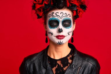 Ürkütücü genç bayan Calavera. Ölüler bayramında sanatsal makyaj yapar. Kırmızı izole edilmiş iskelet gibi giyinmiş siyah deri ceket ve dantel eldiven giyer.