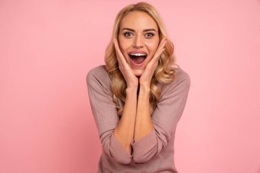Pembe arka planda izole edilmiş heyecanlı genç bir kadın görüntüsü