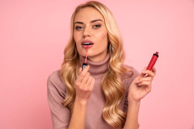 Kapalı fotoğraf güzel harika bayan yeni koleksiyon podone harika sonuç ruj tutun gidin kazak giyin izole Pastel pembe arka plan.