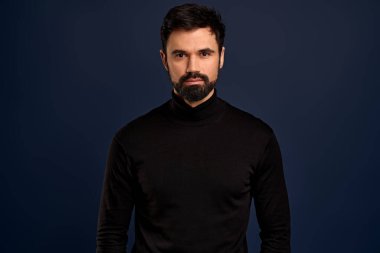 Confident good-looking male entrepreneur in black high neck sweater, smirk and self-assured, standing assertive. Handsome macho man.