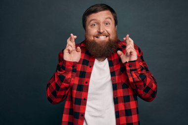 Pozitif düşünce, dua ve inanç kavramı. Umut dolu gülümseyen, iyimser, gri kazaklı yakışıklı, şans için dua eden, iyi haberleri bekleyen, zevk bekleyen, güzel bir anlaşma bekleyen, gri arka plan.