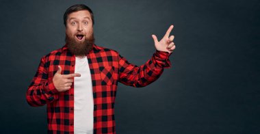 Modern kırmızı kareli gömlekli, etkileyici ve merak uyandıran beyaz erkek model, nefes nefese, vay canına, büyülendim, meraklandım, ilginç bir ürün buldum ve hakkında bilgi topladım..