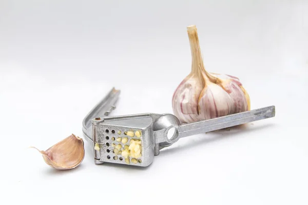 stock image a whole head of garlic with cloves and a garlic chopper crushed the garlic