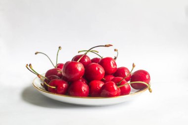 Beyaz bir tabakta bir sürü kırmızı, sulu kiraz