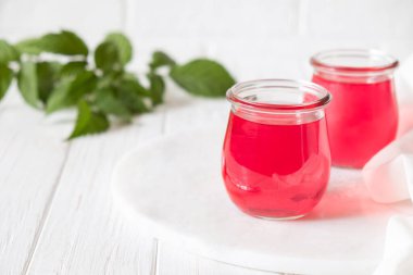 Beyaz arka planda cam kavanozda ahududu aromalı tatlı tatlı puding.