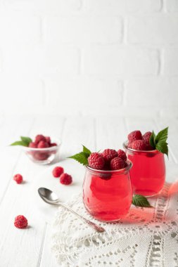 Beyaz arka planda cam kavanozda ahududu aromalı tatlı tatlı puding.