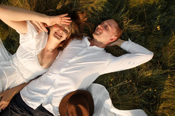 若い幸せな笑顔のカップルが地面に横たわっている畑のピクニックで — ストック写真