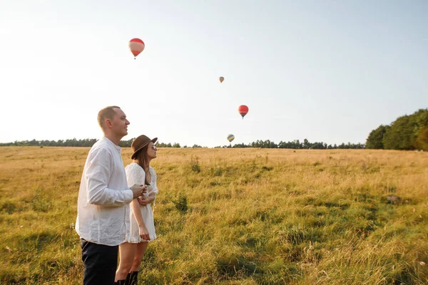 Liefdevol Paar Een Veld Een Achtergrond Van Vliegende Ballonnen — Stockfoto
