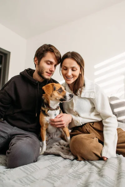 happy couple in love with a beagle dog sitting on the bed