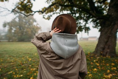 Siste bir ağacın yanında şapkalı şık genç bir kadın.
