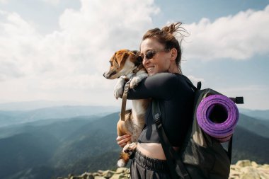 Dağın tepesinde köpeği olan genç bir kadın.