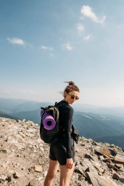 Sırt çantalı genç bir bayan dağın tepesinde.