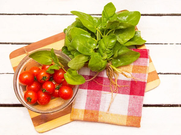 Cherry tomatoes on the plate and a bundle fresh spinach — Stock Photo, Image