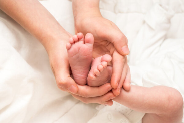 Baby legs. Legs newborn in sister hand