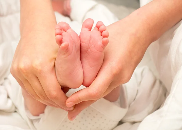 Ножки. Ноги новорожденного в руке сестры — стоковое фото