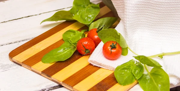 Taze ıspanak ve kiraz domates kesme tahtası üzerinde — Stok fotoğraf