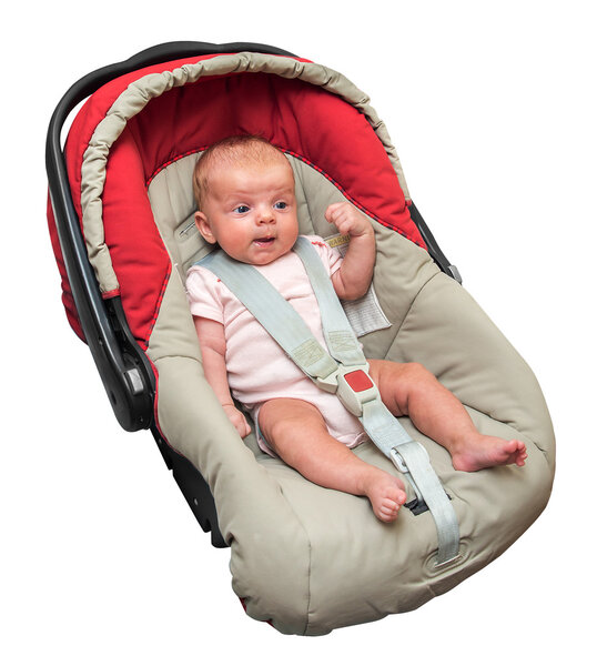Новорожденная девочка сидит в автомобильном кресле с пристегнутым ремнем безопасности

