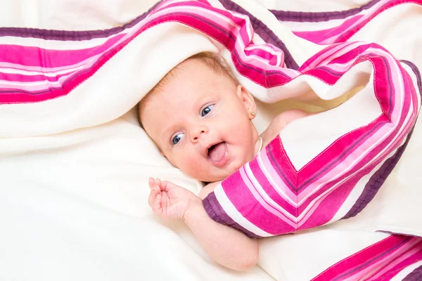 Neugeborenes Mädchen mit blauen Augen auf einer Decke liegend. — Stockfoto