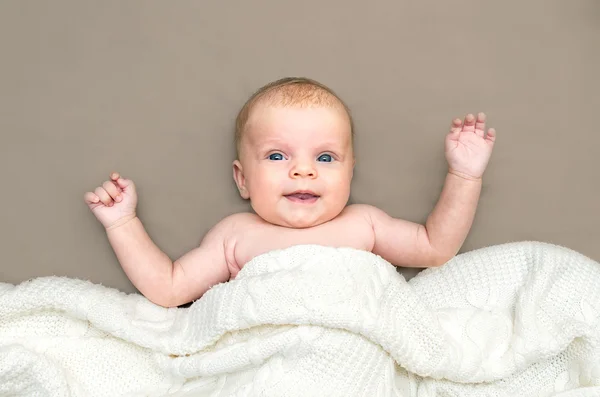 Gelukkig schattig babymeisje met blauwe ogen, liggend op een deken. — Stockfoto