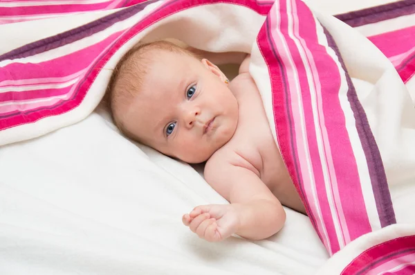 Neugeborenes Mädchen mit blauen Augen auf einer Decke liegend. — Stockfoto