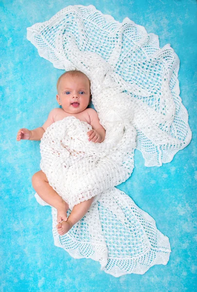 Bonito pequeno bebê de olhos azuis olhando para a câmera deitado na — Fotografia de Stock