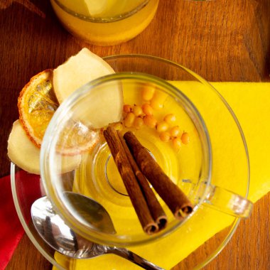 Şeffaf fincan çay için deniz dikenli çilek, zencefil, ahşap bir masada tarçın çubukları. kafe konsepti