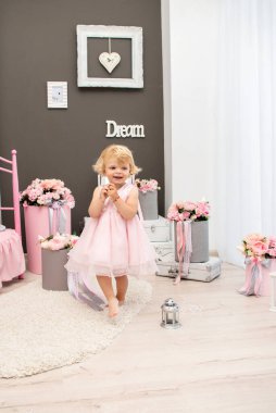 Mutlu küçük kız iki yıl boyunca pembe tonda bir tatil için dekore edilmiş bir odada çiçek oyunu oynadı.