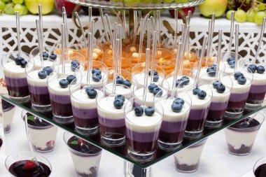 Kaşıkla bardakta çeşitli mini tatlılar. Böğürtlen sütü, kremalı tatlılar.