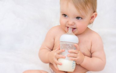 Küçük mutlu kız şişeden süt içiyor. Bebek maması. Yapay besleme kavramı.