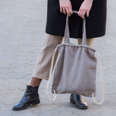 Gri bir tekstil çantası tutan kadın. Ekoloji ya da çevre koruma kavramı. Düzen için beyaz eko çanta.
