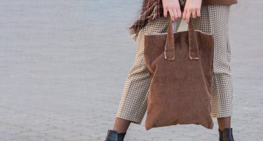 Kahverengi eko tekstil çantası taşıyan bir kadın. Mesaj veya logo için yer var. Ekoloji ya da çevre koruma kavramı. Düzen için kahverengi eko çanta.