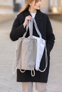 Beyaz ve gri eko çantalar, mesaj atmak için uygun alan ya da bir kızın elinde tasarım. Kıza yavaşça odaklan. Ekoloji ya da çevre koruma kavramı. Çevre dostu kavram.