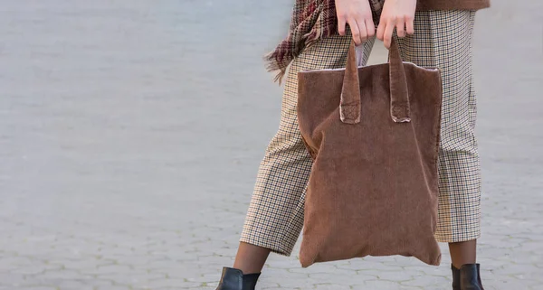 Woman holding brown eco textile bag with place for text or logo. The concept of ecology or environmental protection. Brown eco bag for layout.