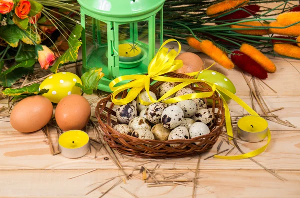 Quail and chicken eggs in a basket and a candlestick — Stock Photo, Image