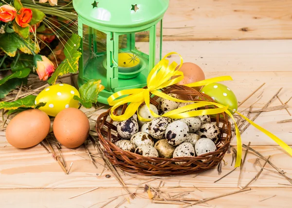 Quail and chicken eggs in a basket and a candlestick, spring fl — Stock Photo, Image