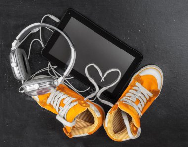 Turuncu spor ayakkabılar, kulaklıklar, tablet .