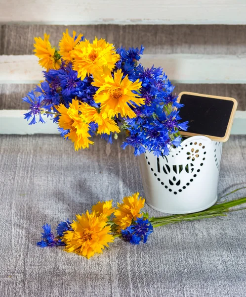 Flores selvagens cores azuis e amarelas em um vaso decorativo com — Fotografia de Stock