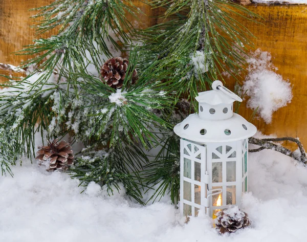 Dekorativa lykta brinner i snön med en granens gren — Stockfoto
