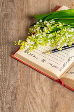 Çiçekler lily vadi üzerinde kitap kayıtları ve bir kalem için