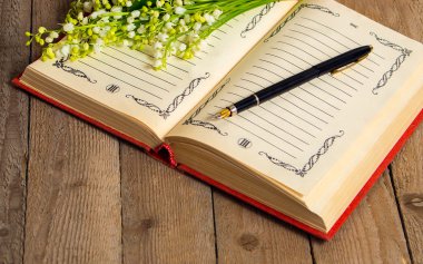 Çiçekler lily vadi üzerinde kitap kayıtları ve bir kalem için