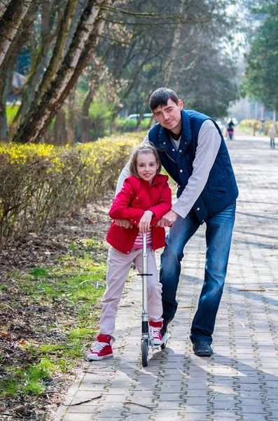 Baba ve kızı bir parkta bir yürüyüş bir scooter üzerinde — Stok fotoğraf