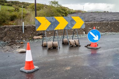 Mavi zeminde beyaz oklu trafik konileri yol çalışmalarını gösteriyor