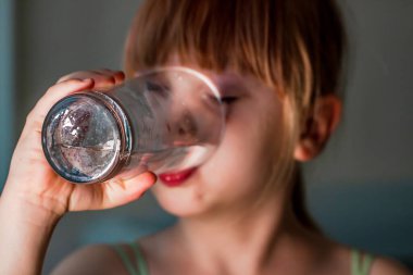 Küçük kız bir bardak su içiyor.