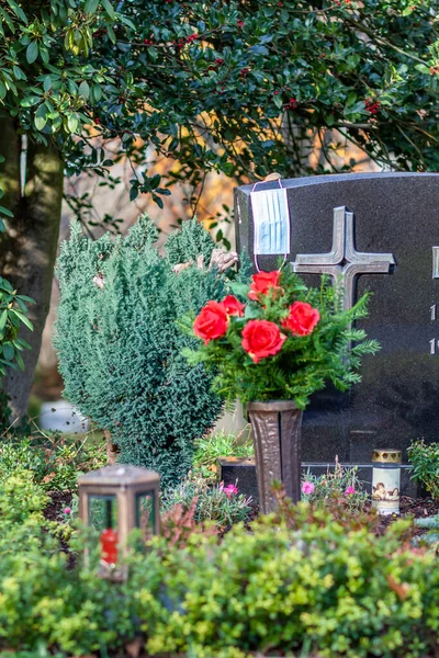 Gesichtsmaske, die während der Pandemie auf dem Grab von Familienmitgliedern liegt — Stockfoto
