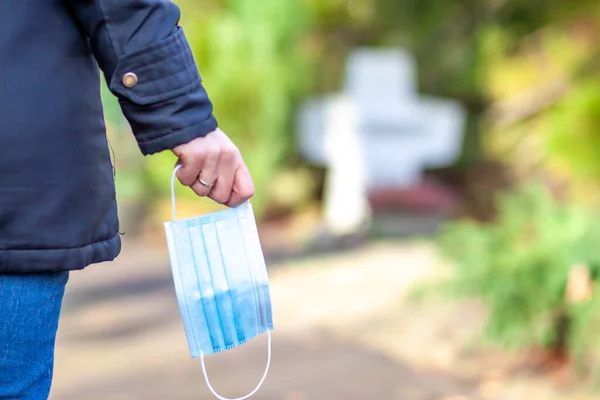 Frau, die während der Pandemie mit einer Gesichtsmaske am Grab von Familienmitgliedern steht — Stockfoto