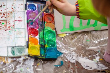 Salgın sırasında evde suluboya kullanan küçük bir kız.