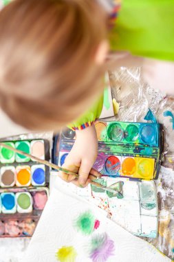 Salgın sırasında evde suluboya kullanan küçük bir kız.