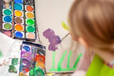 Salgın sırasında evde suluboya kullanan küçük bir kız.