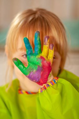 Salgın sırasında evde suluboya boyasının arkasına saklanan küçük bir kız.